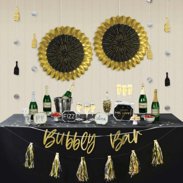 Happy New Year Bubbly Bar Decorating Kit in black, silver, and gold with banners, fans, signs, and reusable stirrers.