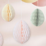 Hanging honeycomb egg decorations in cream, light pink, and sage green for festive Easter celebrations.