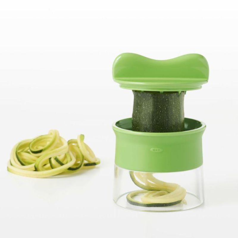 Hand-held spiralizer transforming vegetables into spaghetti-like strands with non-slip grip and safety food holder.