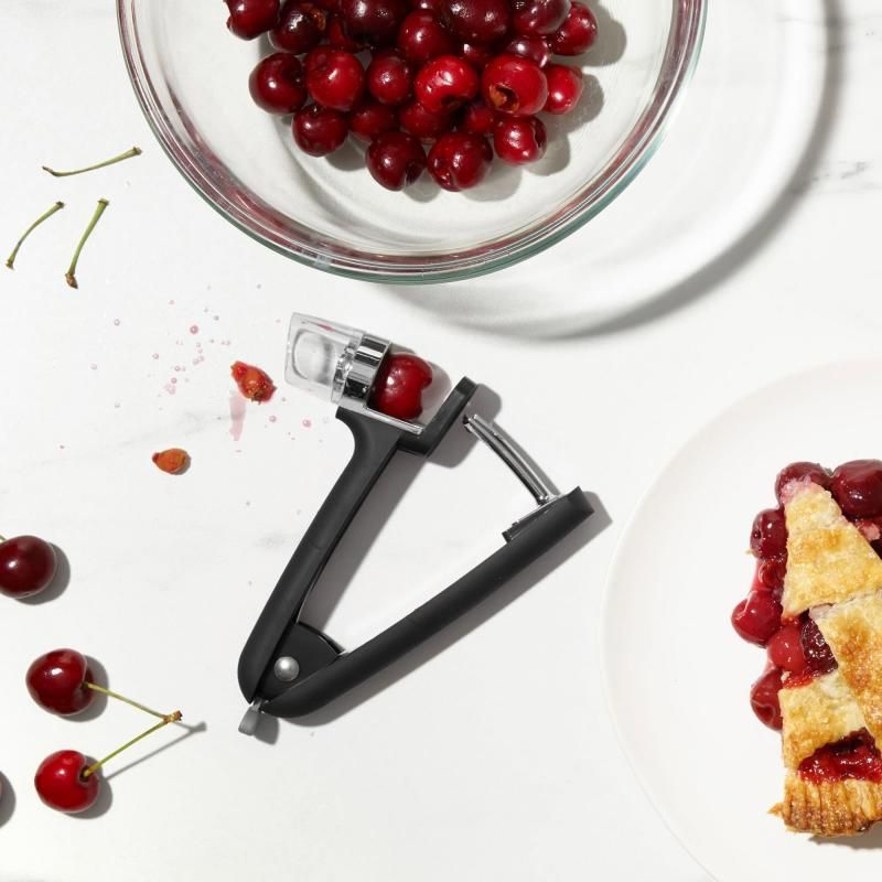 OXO Good Grips Cherry & Olive Pitter with removable splatter shield, ergonomic handles, and durable die-cast zinc construction.