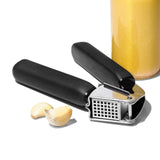 OXO Good Grips Garlic Press with ergonomic handles, stainless steel construction, and large hopper for easy garlic crushing.