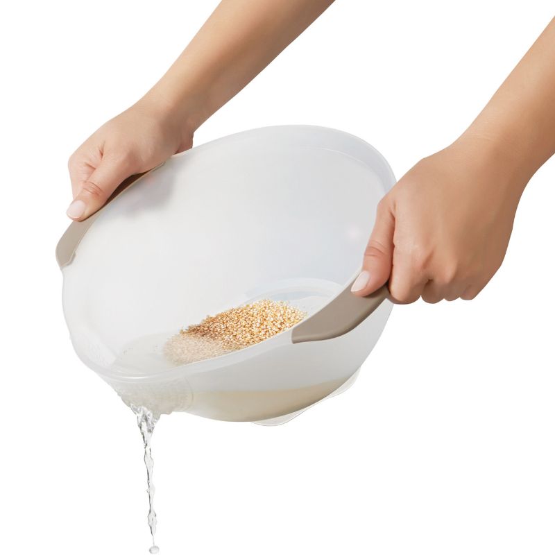 OXO Rice & Grain Washing Colander with unique holes for efficient rinsing of small grains and berries, featuring a pour spout and non-slip handles.