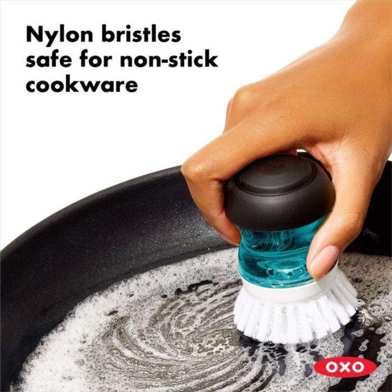 Ergonomic OXO Good Grips Soap Dispensing Palm Brush with button-activated soap dispensation and safe nylon bristles for easy cleaning.