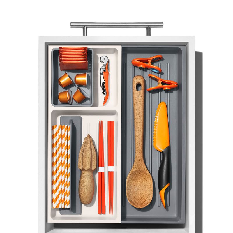 Expandable kitchen tool drawer organizer with adjustable dividers and storage cup for efficient utensil storage.