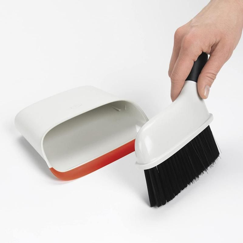 Compact OXO Good Grips dustpan and brush set, featuring a snap-in design, rubber lip for dirt pickup, and angled brush handle.