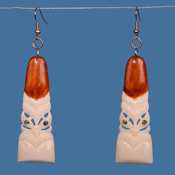 Bone Toki Earrings featuring a Tiki face, handcrafted from beef bone with paua shell accents, symbolizing Maori heritage.