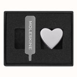 Silver heart pin for Moleskine notebooks, crafted from zinc alloy, adds elegance and personal flair to stationery.