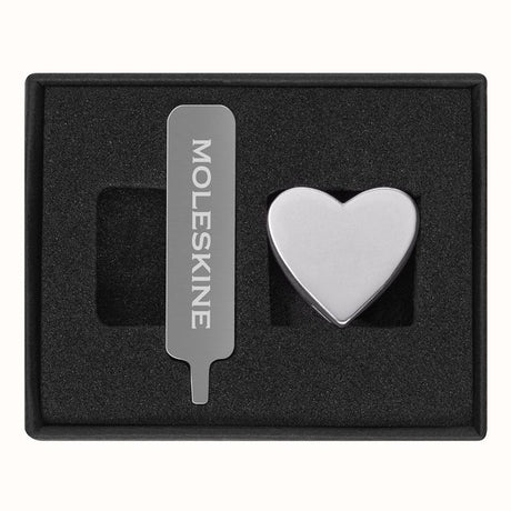 Silver heart pin for Moleskine notebooks, crafted from zinc alloy, adds elegance and personal flair to stationery.