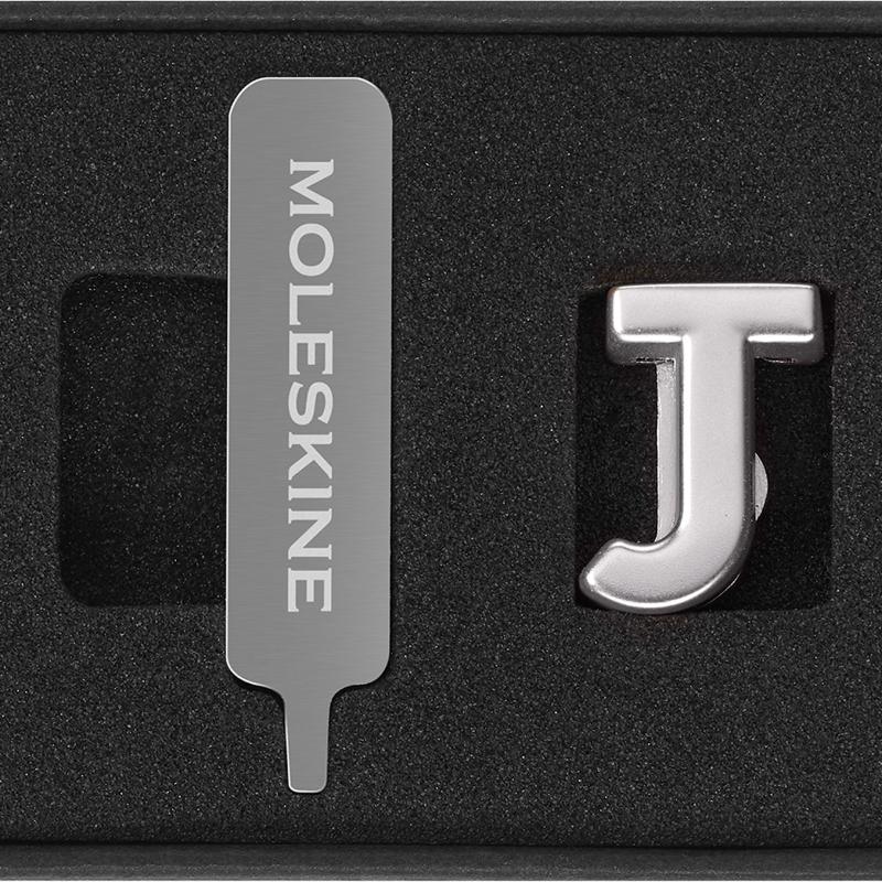 Stylish Moleskine Pins J Silver letters for notebook closures, customizable with initials or words for personal flair.