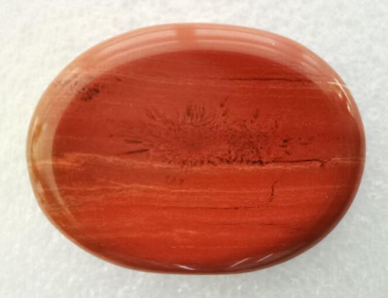 Red jasper oval worry stone, 4.5cm, perfect for anxiety relief and promoting calmness in hand. Ideal for mindfulness practices.