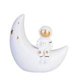 Playful Moon Astronaut Table Lamp for kids, featuring a golden glow, crescent moon, and metallic stars, safe LED design.