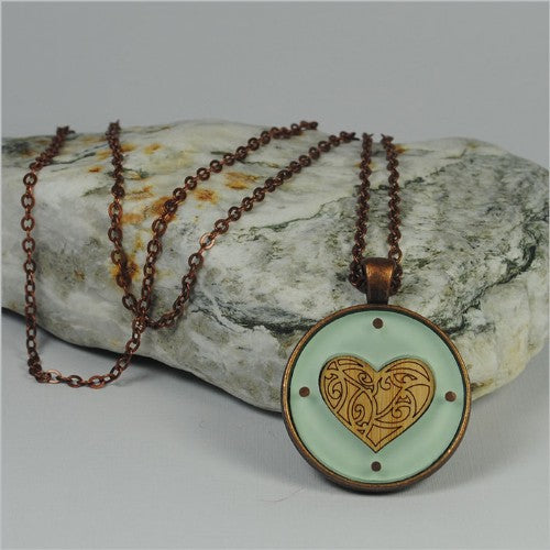 Circle Pendant Necklace featuring a Kowhaiwhai heart in green, crafted from etched bamboo veneer and vibrant acrylic.