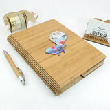 Eco-friendly bamboo journal with floral tui design, ideal for jotting down thoughts and creativity on the go.