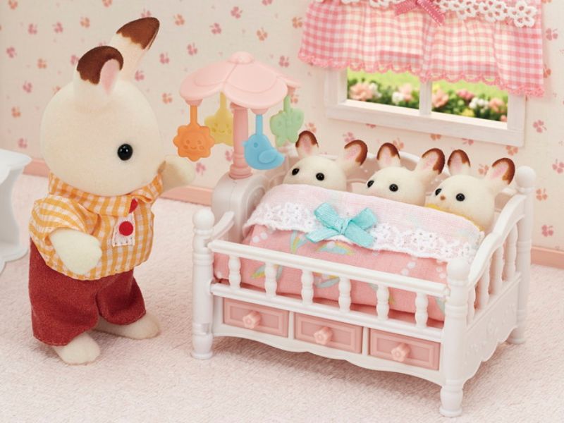 Crib with mobile for triplet babies featuring a spinning floral mobile and three storage drawers for imaginative play.