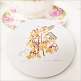 Acrylic coaster featuring Sarah Featon's vibrant Kowhai flower illustration, 10cm, with a cork base for durability.