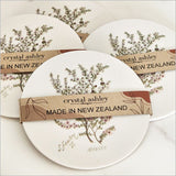 Acrylic coaster featuring vibrant Sarah Featon Manuka flower illustration, ideal for beverages and home decor, 10cm diameter.