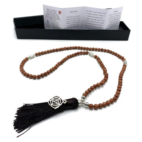 Mala beads made of natural goldstone with 108 beads and a root chakra charm, perfect for meditation and spiritual practices.