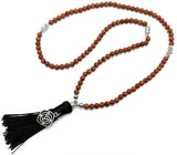 Mala beads made of goldstone with a root chakra charm, ideal for meditation, mindfulness, and stylish everyday wear.