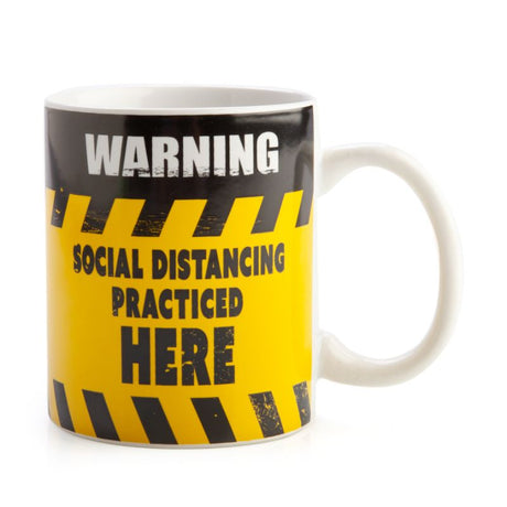 Ceramic coffee mug with a humorous social distancing warning sign design in bold black and yellow colors.