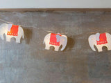 Whimsical fairy lights with 10 elephant designs in vibrant red blankets, perfect for kids' rooms and festive decor.
