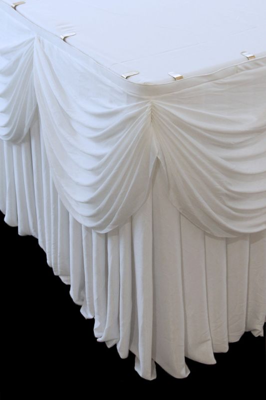 Elegant white pleated table skirt with swag, featuring Velcro for easy attachment, perfect for events and parties.