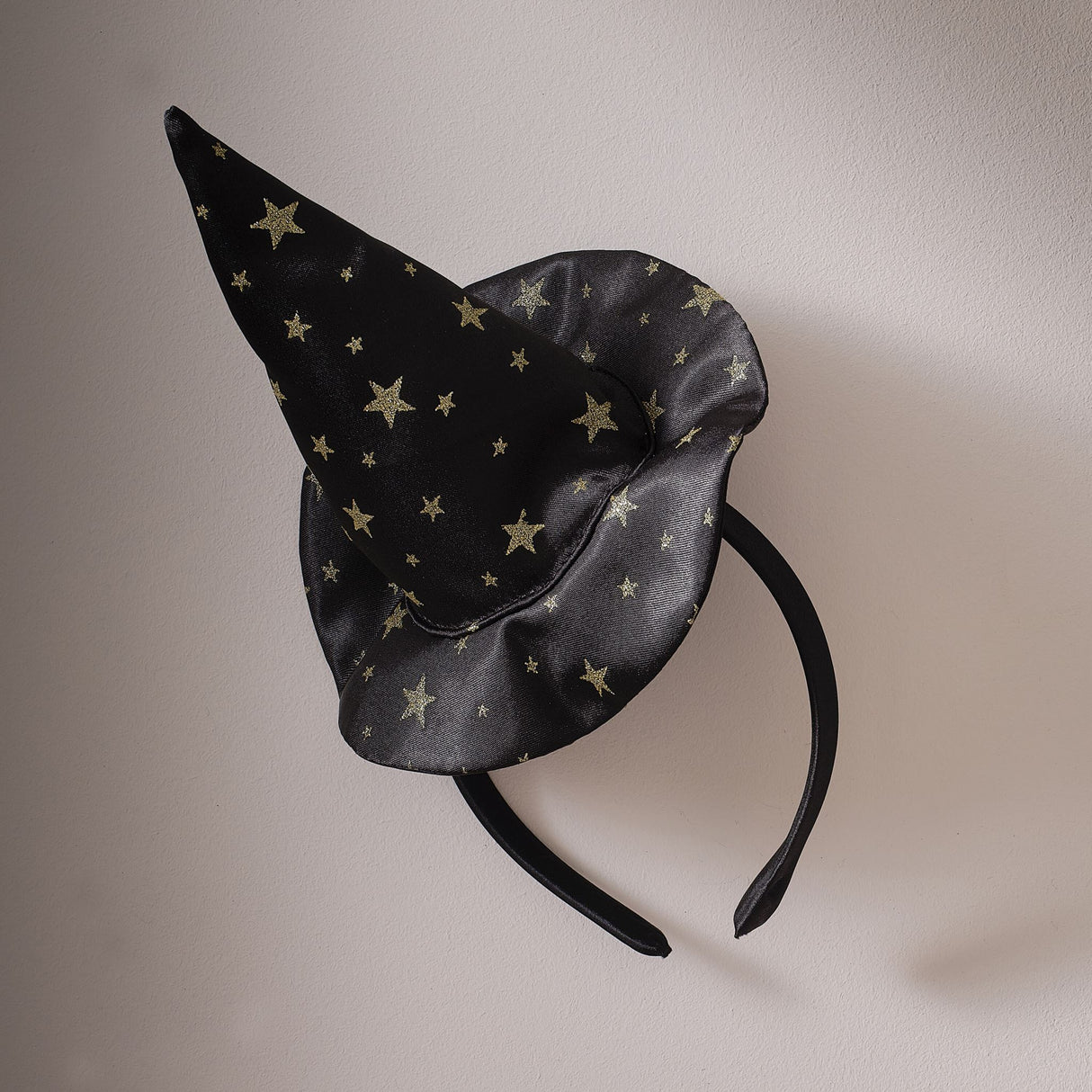 Black satin witch hat headband with shimmering gold star embellishments, perfect for Halloween costumes and parties.