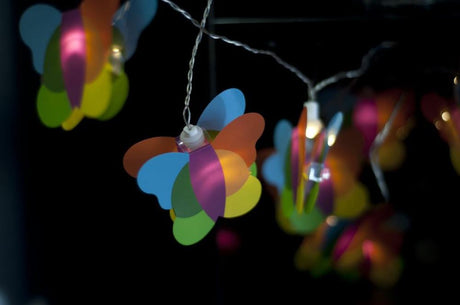 Colorful butterfly fairy lights on a clear wire, perfect for creating a magical ambiance in children's rooms and parties.