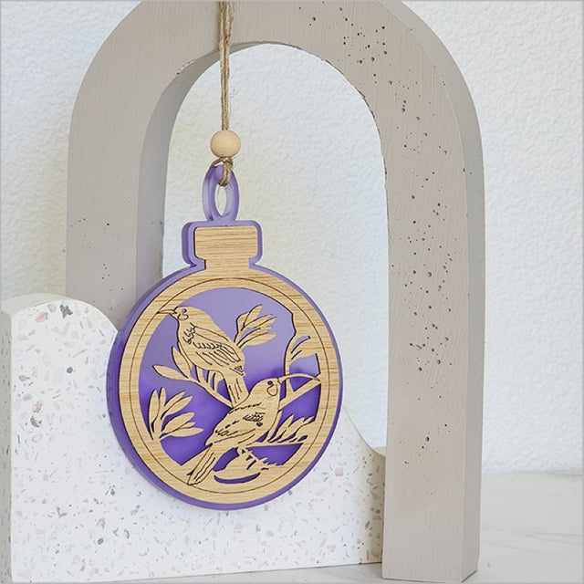 Elegant purple satin acrylic bauble ornament featuring a Huia bird design, perfect for holiday decor or gifting.