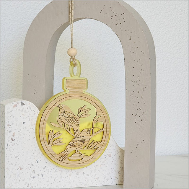 A vibrant yellow satin acrylic bauble ornament featuring intricate Huia detailing, perfect for festive decor or thoughtful gifts.
