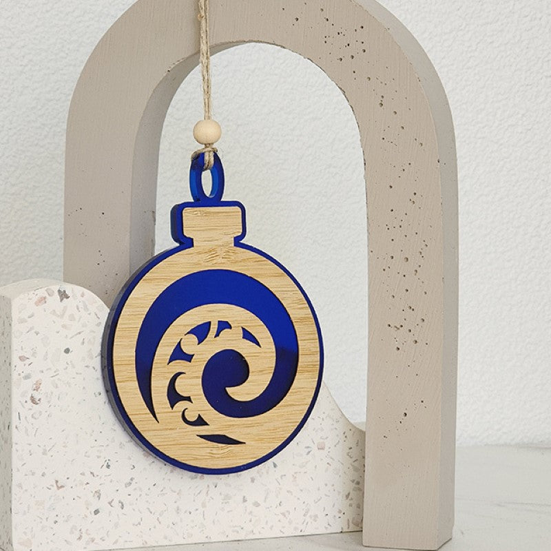 Blue satin acrylic hanging ornament featuring a unique Koru design, crafted from laser-cut bamboo, ideal for holiday decor.