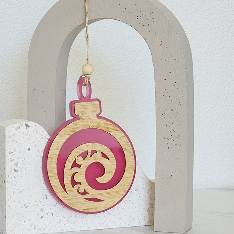 Pink satin acrylic bauble ornament with intricate Koru design, perfect for home decor and festive decorations.