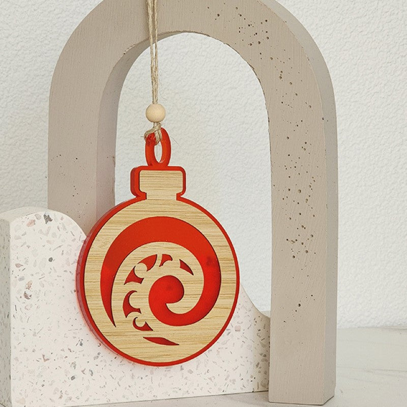 Red satin acrylic Koru hanging ornament, 80mm x 110mm, featuring an intricate laser-cut design symbolizing growth.