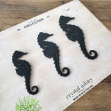 Acrylic wall art set featuring elegant black seahorse designs in three sizes, perfect for modern coastal decor.