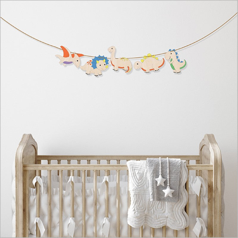 Colorful DIY dinosaur garland kit for kids, featuring laser-cut pine pieces, paints, and twine for creative decorating.