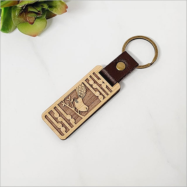 Eco-friendly bamboo keyring featuring a Fantail and Koru design, celebrating New Zealand’s nature and culture.