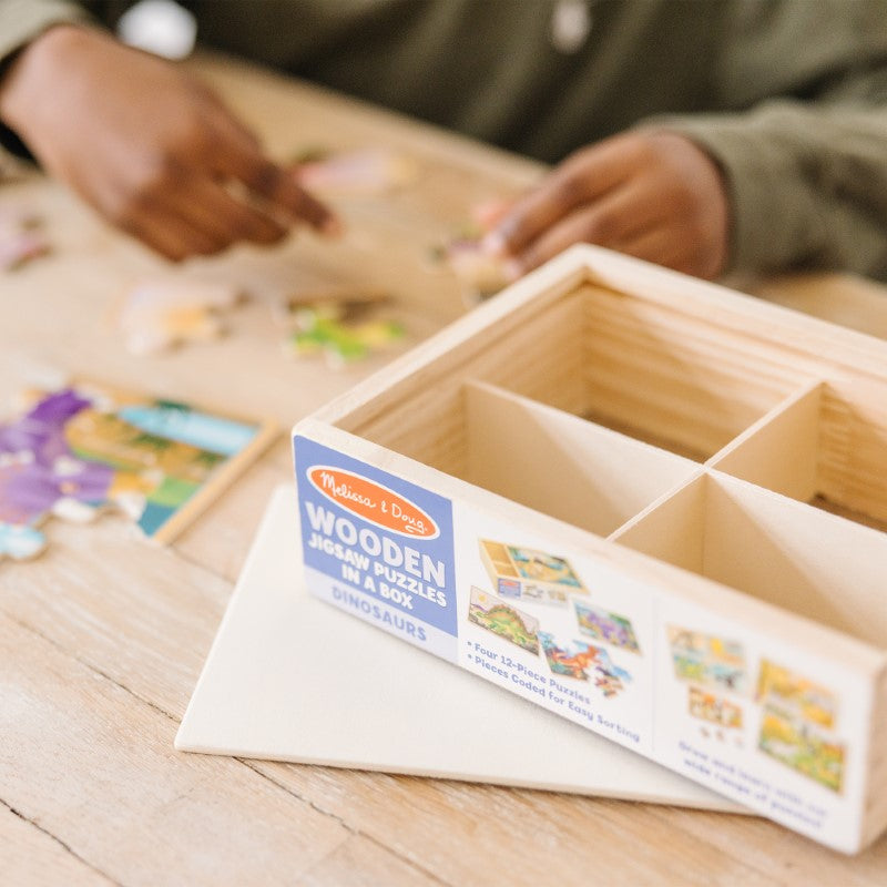 Colorful dinosaur puzzles in a wooden box, featuring Triceratops, Apatosaurus, Stegosaurus, and T-Rex for ages 3+.