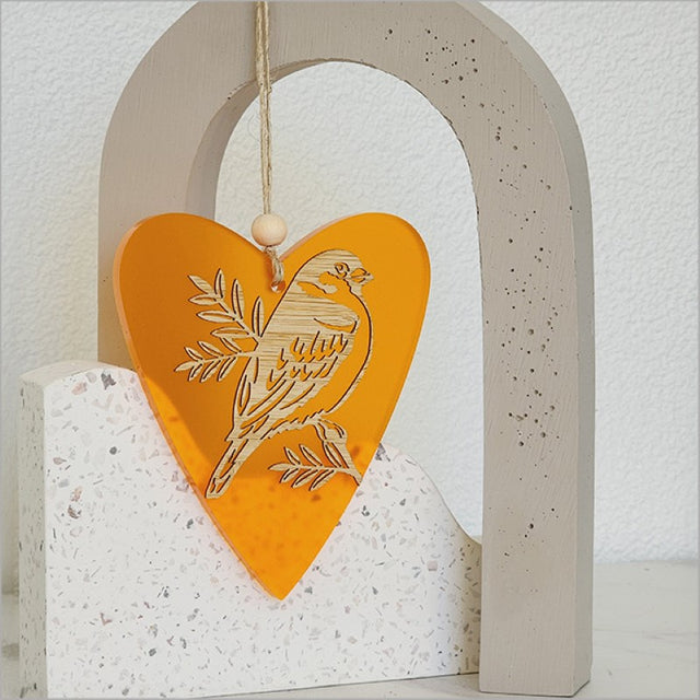 Heart-shaped orange satin acrylic ornament featuring sparrow and pihoihoi design, ideal for home decor and gifting.