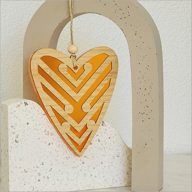 Heart-shaped orange satin acrylic ornament featuring intricate Koru designs, ideal for home decor and gifting.