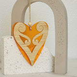 Vibrant orange heart-shaped hanging ornament featuring intricate Koru patterns, crafted from laser-cut bamboo and satin acrylic.