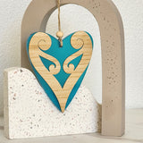 Teal satin acrylic heart ornament with koru design, perfect for home decor or gifting, measuring 90x105mm.