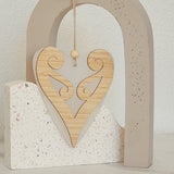 Elegant white satin acrylic heart ornament featuring a delicate Koru design, perfect for modern home decor. 90mm x 105mm.