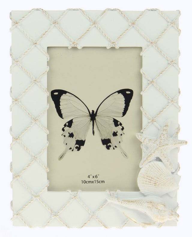 White fishing net frame adorned with seashells, perfect for coastal decor and showcasing cherished beach memories.