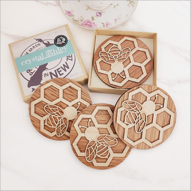 Handcrafted bamboo and rimu coasters featuring intricate bee designs, perfect for eco-friendly home decor.