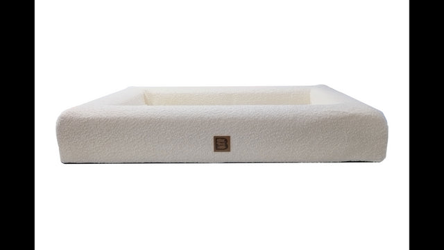 Luxurious cream orthopedic dog bed with plush Boucle fabric, supportive foam, and bolstered walls for comfort and security.