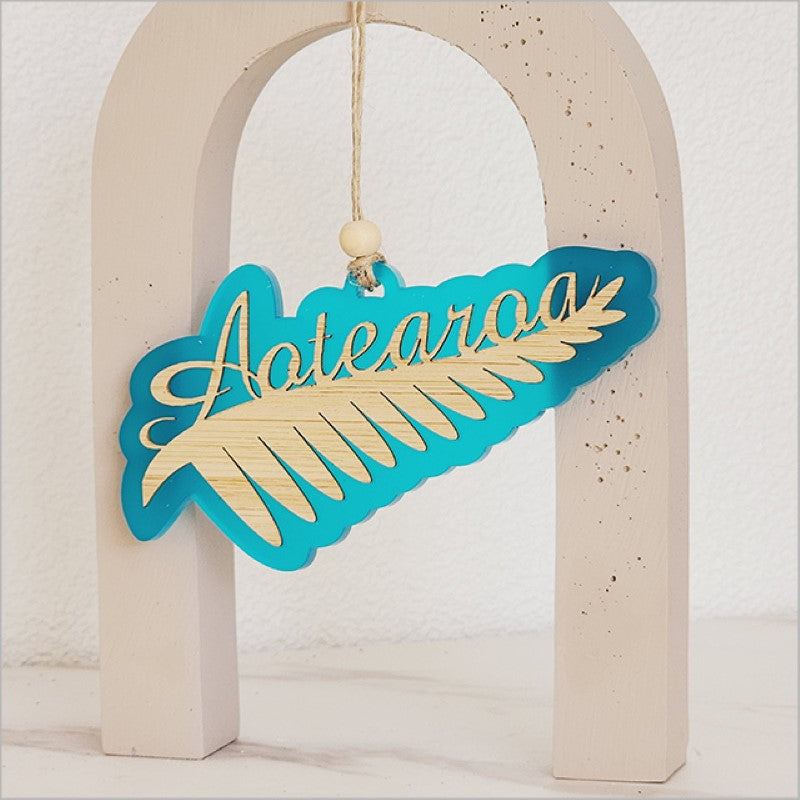 Teal satin acrylic hanging ornament featuring a laser cut Silver Fern design, perfect for home decor or gifts.