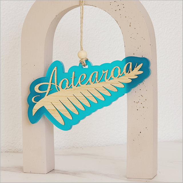 Teal satin acrylic hanging ornament featuring a laser cut Silver Fern design, perfect for home decor or gifts.