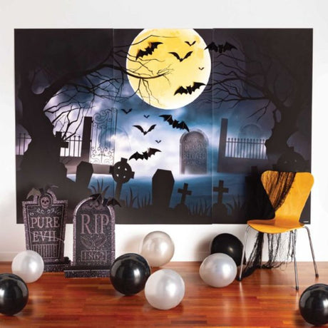 Spooky graveyard scene setters kit with plastic sheets, tombstones, and cardboard bats for Halloween decor. Pack of 12.