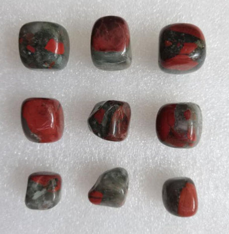 Loose tumbled stones of Dragon's Blood Jasper in vibrant colors, perfect for crystal healing and decoration.