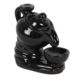 Black ceramic tea pot backflow incense burner, featuring delicate smoke cascading from the spout into the cup for relaxation.