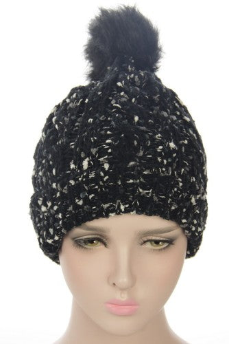 Black textured beanie with fleece lining, fur pom pom, and stylish design for warmth and comfort in winter.
